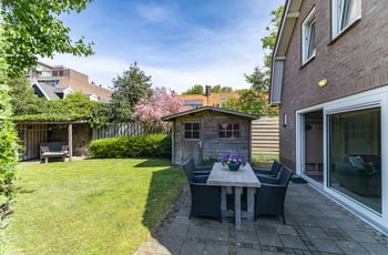 Overzicht van de tuin met tuinhuisje en eettafel